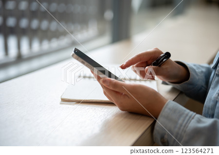 A close up of the left hand holding smartphone and right hand pointing at the phone screen. A close up of the left hand holding smartphone and right hand pointing at the phone screen. 123564271