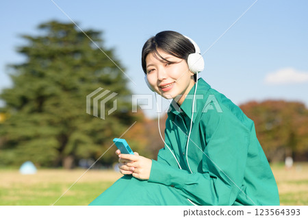 A young woman listening to music outdoors A young woman listening to music outdoors 123564393