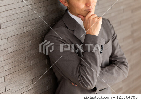 A middle-aged male businessman wearing a gray suit thinking 123564703