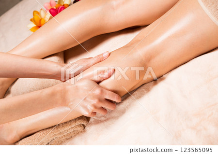 Young Asian woman is getting a calf massage. Young Asian woman is getting a calf massage. 123565095
