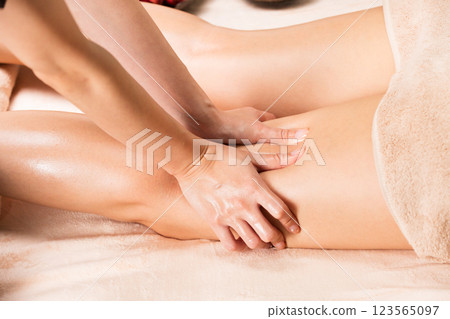 A woman is getting an oil massage on her thighs. 123565097
