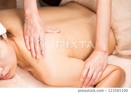 一位年輕的亞洲女性正在接受背部精油按摩。 123565100