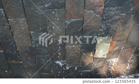 Water Cascading Over Textured Stone Wall 123565435