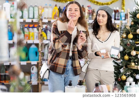 Two girl friends choose eyeshadow and lip stick while shopping 123565908