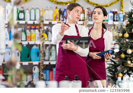 Two saleswomen fill in the tables on the planchette against the background of the Christmas tree Two saleswomen fill in the tables on the planchette against the background of the Christmas tree 123565996