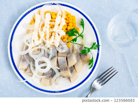 Slices of spicy marinated herring fillet with corn and onion 123566083
