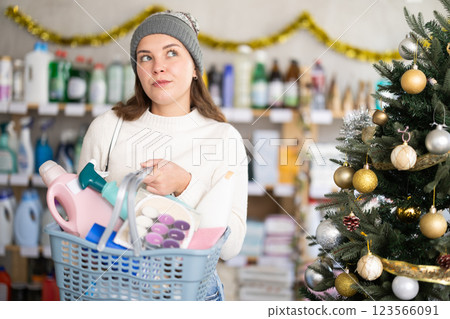 Young girl with full basket choosing something in supermarket during X-mas 123566091