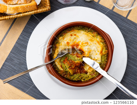 On wooden table traditional Italian dish is lasagna baked in oven under cheese crust. 123566110