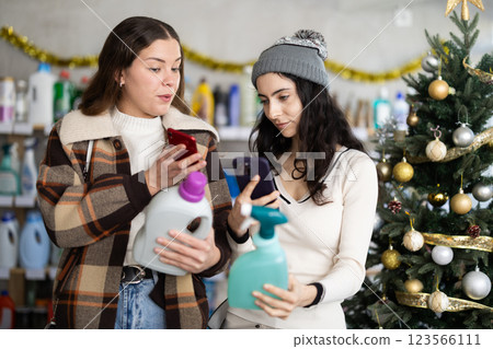 Young girls scanning QR-code on cleaning spray in store during Christmas 123566111