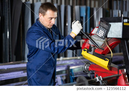 Adult man cuts profile pipe on machine 123566112