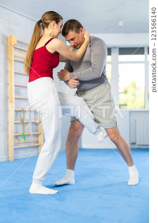 Young woman learns to fight back against an attacking man during self-defense training at gym Young woman learns to fight back against an attacking man during self-defense training at gym 123566140