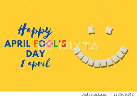 April Fool's Day, smile made from refined sugar cubes on a yellow background, top view, with text 123566148