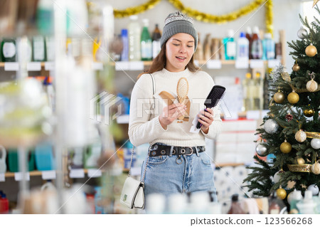 Young girl choosing comb in store with New Year decoration Young girl choosing comb in store with New Year decoration 123566268