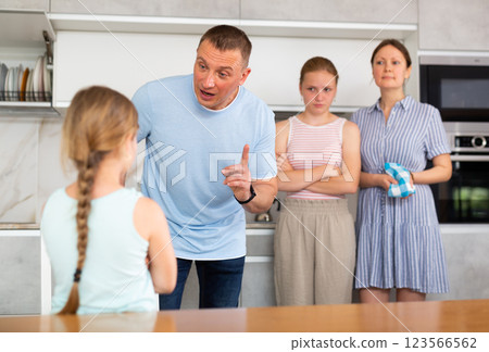 Girl with hair in braids stands in front of parents and listens to instructions about bad behavior Girl with hair in braids stands in front of parents and listens to instructions about bad behavior 123566562