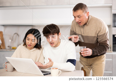 Friendly family watches something together on the Internet or video chats via laptop Friendly family watches something together on the Internet or video chats via laptop 123566574