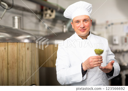 Brewer with glass filled with fresh hops at brewery 123566692