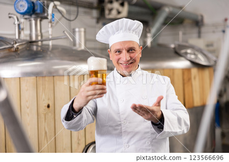 Cheerful man brewer presenting glass of beer 123566696
