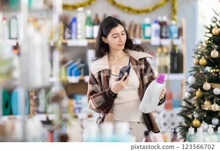 Young woman scanning QR-code on detergent in store during Christmas Young woman scanning QR-code on detergent in store during Christmas 123566702