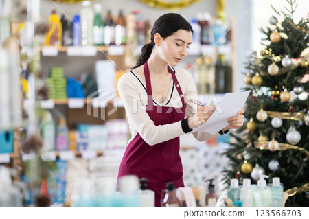 Young woman restocking using paper in store with New Year decoration Young woman restocking using paper in store with New Year decoration 123566703