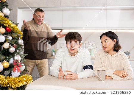 Domestic quarrel during Christmas celebration - father scolds and shouts at young gyuy and girl 123566820