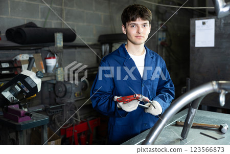 Young guy posing with vice in workshop Young guy posing with vice in workshop 123566873