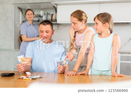 Joyful daughters surrounded dad in kitchen and asked for money 123566900
