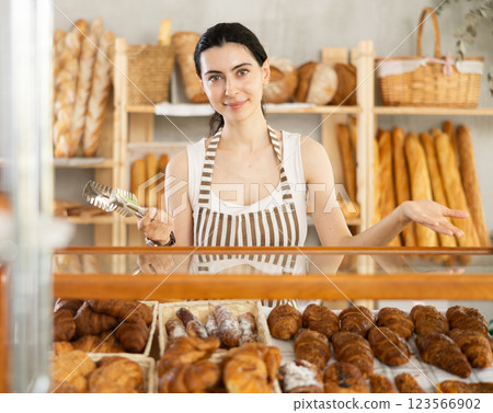 Young woman seller at showcase with pastries 123566902