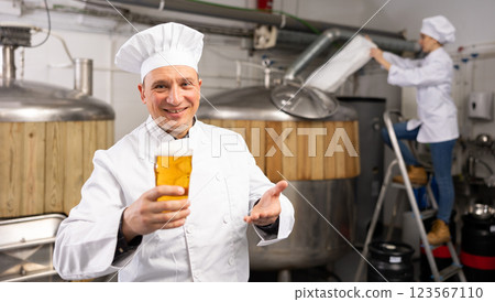 Brewer is standing with beer with foam in glass on his workplace 123567110