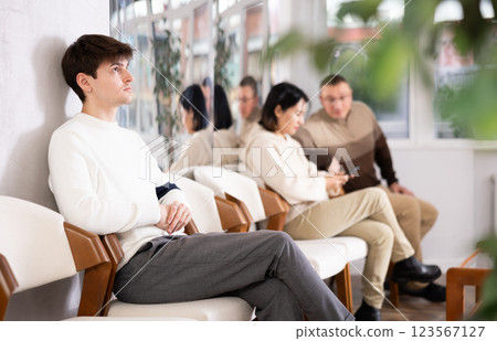 Young guy sits in line at reception Young guy sits in line at reception 123567127