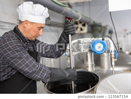 Beer factory worker mixing beer in tank Beer factory worker mixing beer in tank 123567154
