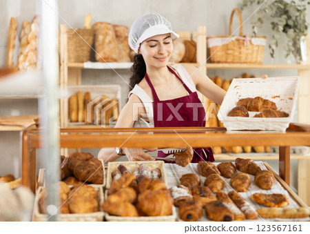 Young woman seller puts croissants in showcase Young woman seller puts croissants in showcase 123567161