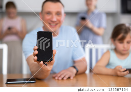 Father showing the screen of her phone. Children and husband typing on smartphone screen Father showing the screen of her phone. Children and husband typing on smartphone screen 123567164