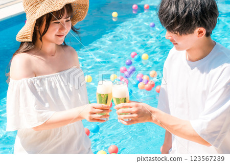 一對夫婦在度假酒店的泳池邊舉著啤酒杯乾杯 123567289