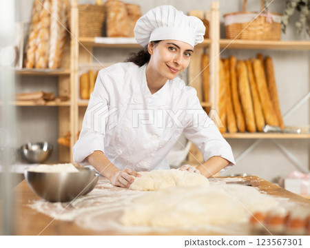 Young woman works in bakery as baker, kneads dough, works with flour. Young woman works in bakery as baker, kneads dough, works with flour. 123567301