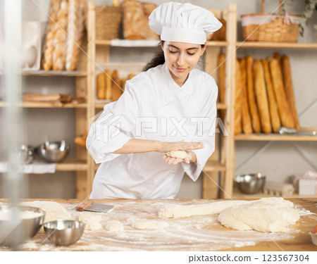Young woman works as baker, mold buns from dough, creates pastry from dough. 123567304