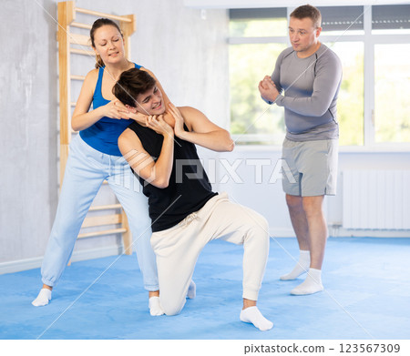 Guy and woman train to perform defense of strangling opponent, while learning self-defense Guy and woman train to perform defense of strangling opponent, while learning self-defense 123567309