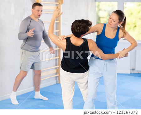 Guy and woman train to perform defense of strangling opponent, while learning self-defense 123567378