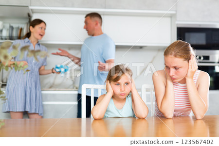 Children feels upset while parents quarrel at background. Sad little girl and boy frustrated with psychological problem caused by mom and dad arguing, family conflicts or divorce impact on child Children feels upset while parents quarrel at background. Sad little girl and boy frustrated with psychological problem caused by mom and dad arguing, family conflicts or divorce impact on child 123567402