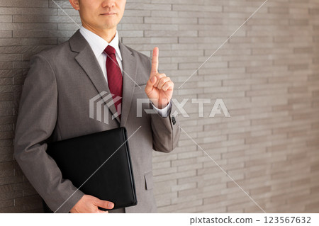 A middle-aged male businessman in a suit pointing his index finger 123567632