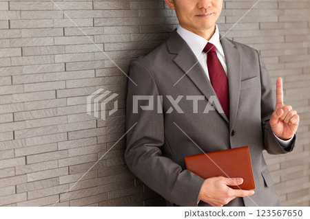 一位身穿西裝的中年男性商人指著他的食指 123567650