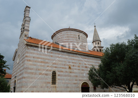 Budva, Montenegro picturesque old town and fortress walls architecture. Stunning showcasing historic stone buildings with red-tiled roofs traditional house. Spire of the chapel of The Church of Sveti Budva, Montenegro picturesque old town and fortress walls architecture. Stunning showcasing historic stone buildings with red-tiled roofs traditional house. Spire of the chapel of The Church of Sveti 123568010