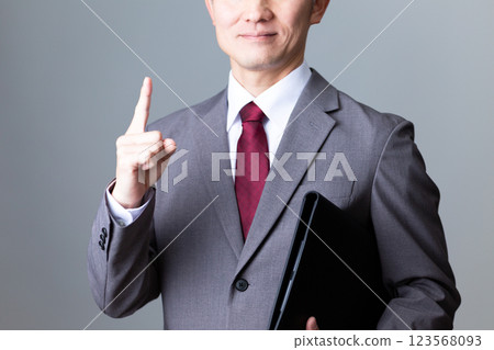 A middle-aged male businessman in a suit pointing his index finger A middle-aged male businessman in a suit pointing his index finger 123568093