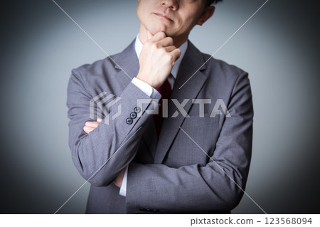 A middle-aged male businessman wearing a gray suit thinking 123568094