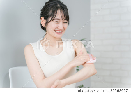 Asian woman puffing sunscreen and antiperspirant body powder on her arm 123568637