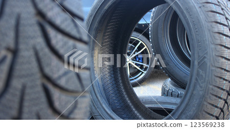 Variety stacked tires in front of the car wait for tire changes service. Vehicle stand behind pile of tires at car workshop Variety stacked tires in front of the car wait for tire changes service. Vehicle stand behind pile of tires at car workshop 123569238