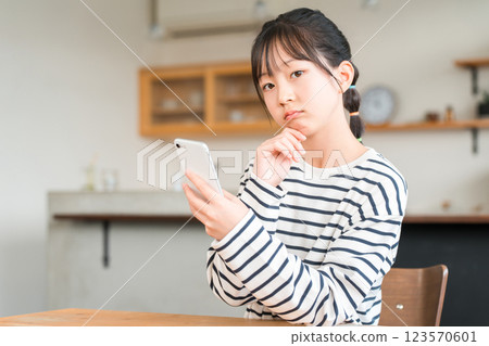 Elementary and junior high school girls using smartphones in the living room and dining room at home 123570601