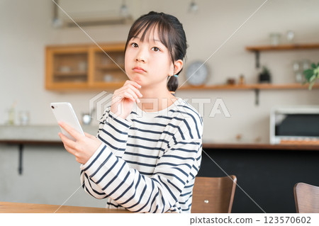 Elementary and junior high school girls using smartphones in the living room and dining room at home 123570602