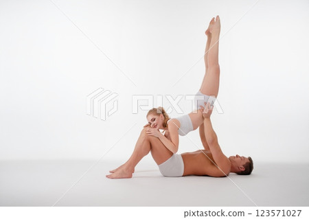 Couple engages in dynamic acrobatic pose in a studio setting Couple engages in dynamic acrobatic pose in a studio setting 123571027