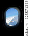 View from airplane window showing wing and coastal landscape during daytime flight 123571342