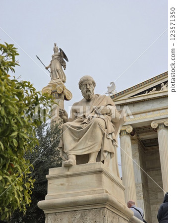 Renowned ancient philosopher statue in Athens with goddess Athena in the background 123571350